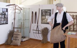 Ausstellung mit landwirtschaftlichem Gerät, Mannequin und historischen Fotos