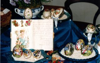 Dekorativ bemalte Ostereier auf Schalen mit Reis und ein geöffnetes Buch.