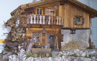 Handgefertigte Miniatur-Holzhütte mit Balkon, Baum und dekorativem Moos.