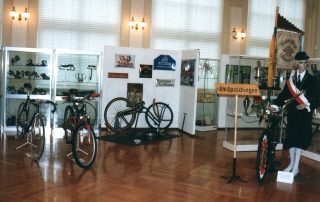 Ausstellung mit historischen Fahrrädern, Fahrradteilen in Vitrinen, alten Werbeschildern.