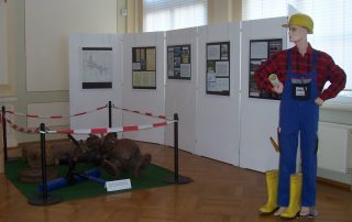 Ausstellung mit Arbeiterpuppe, Infotafeln und abgetrennten Wasserrohrteilen.